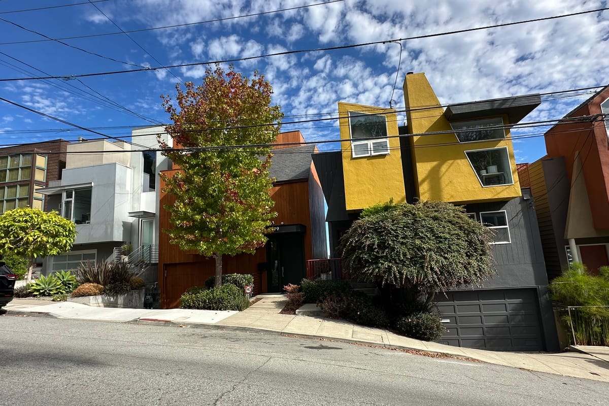 Contemporary houses in cedar, white stucco and mustard yellow stepping up a steep Bernal Heights block in San Francisco.