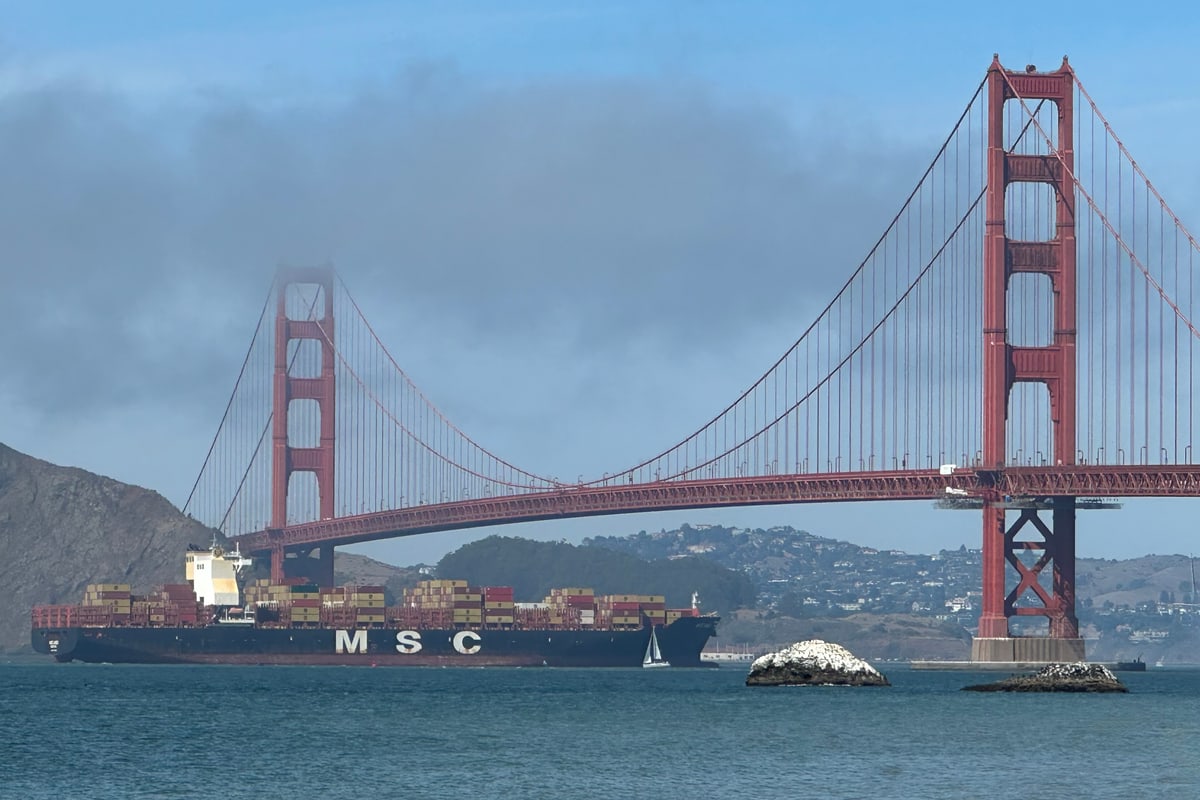 The Golden Gate Bridge seen from Baker Beach at the western edge of Sea Cliff, San Francisco, a container ship passing beneath and the Marin Headlands behind.